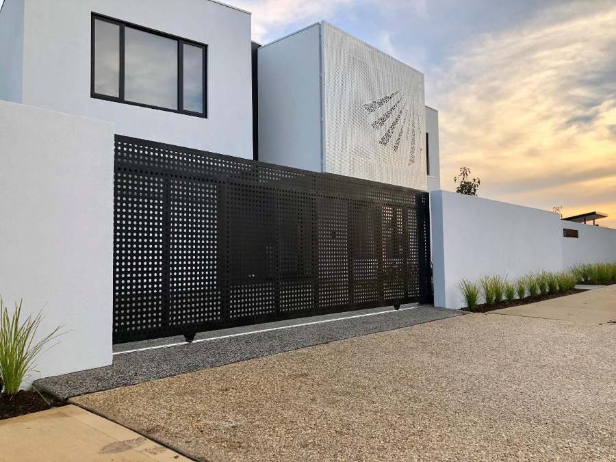 Rendered front fence with a perforated steel sliding gate on a modern white house