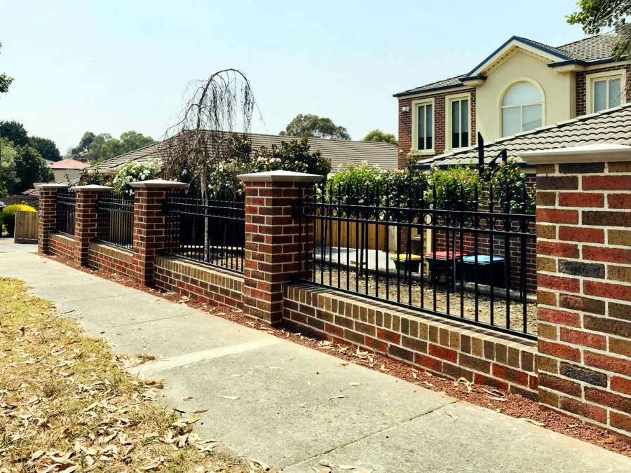 Red brick fence with black iron panels